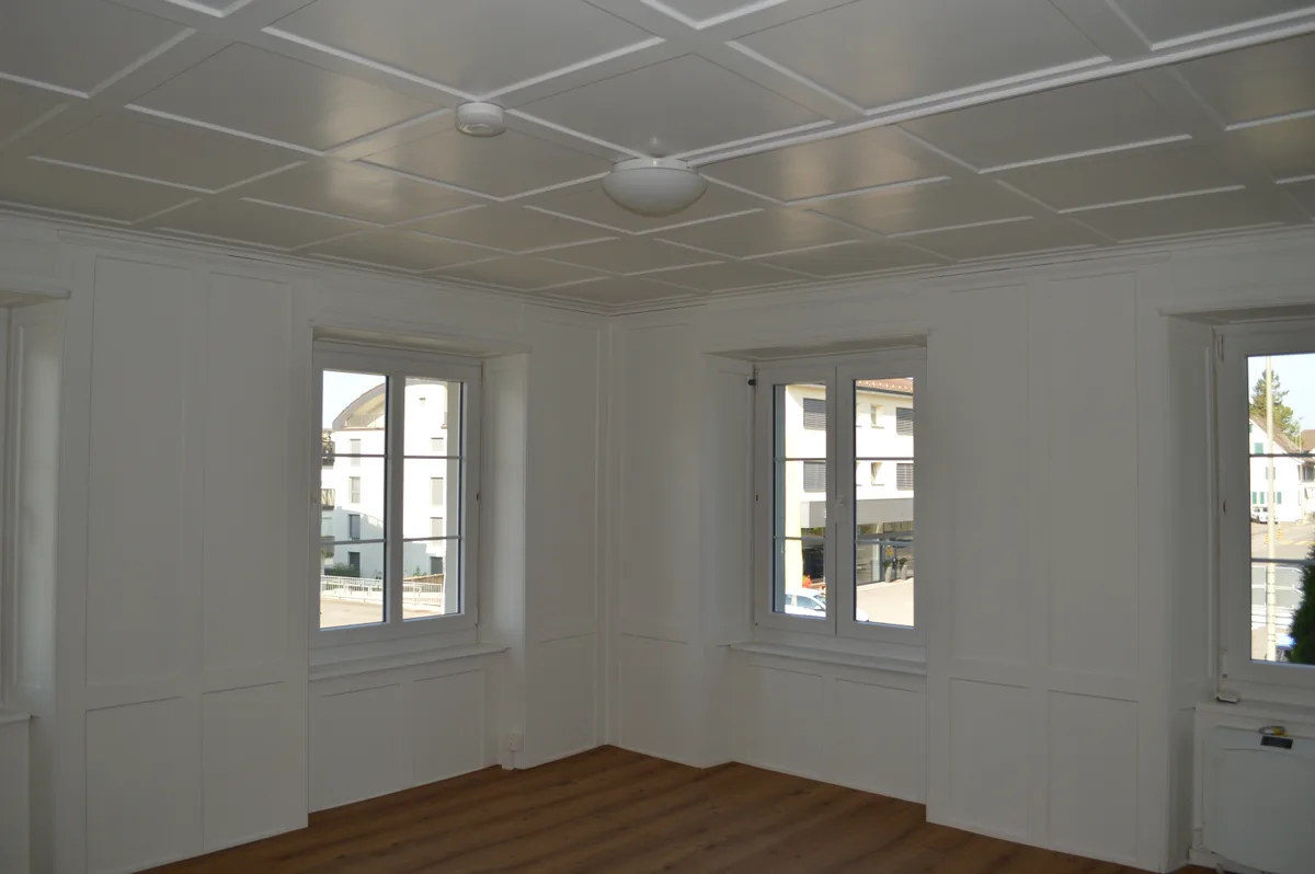 Ein helles Zimmer mit Parkettboden und Deckenstruktur.